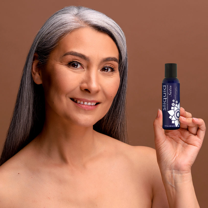 Model posing with Sliquid Satin 2oz bottle for menopausal women.